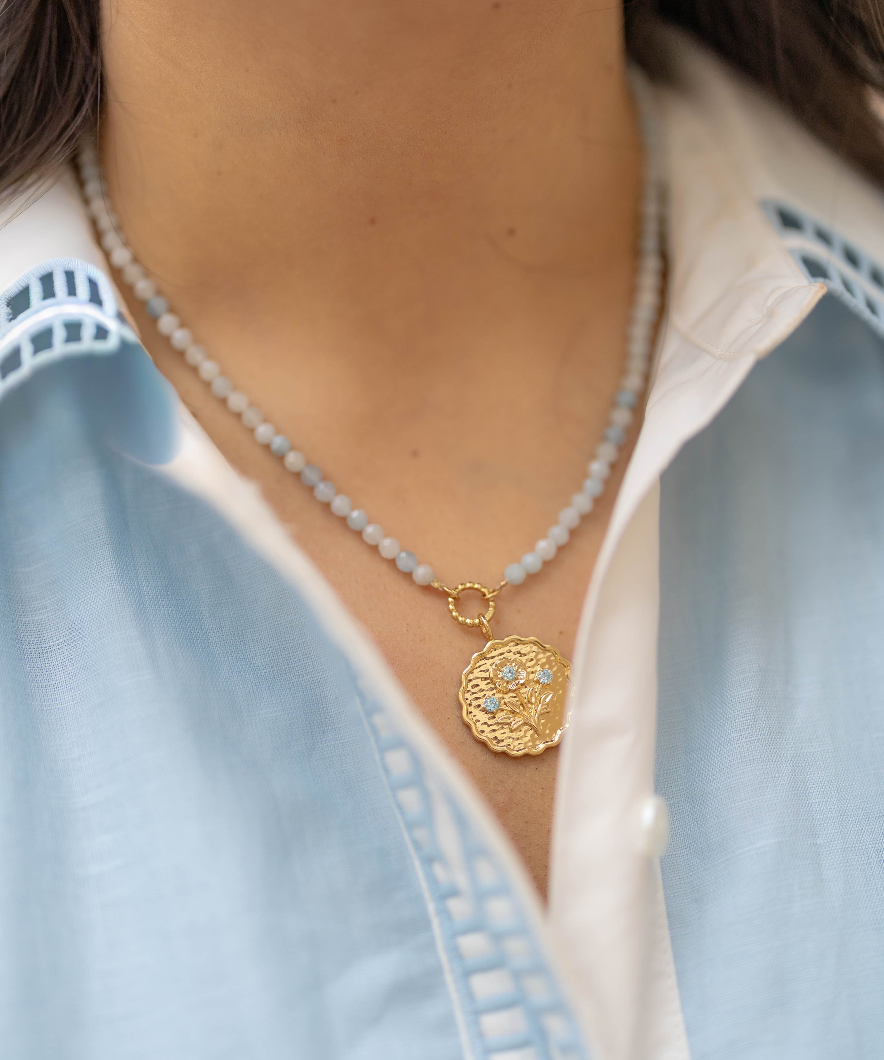 blue beaded necklace with a gold pendant floral charm with blue gemstones