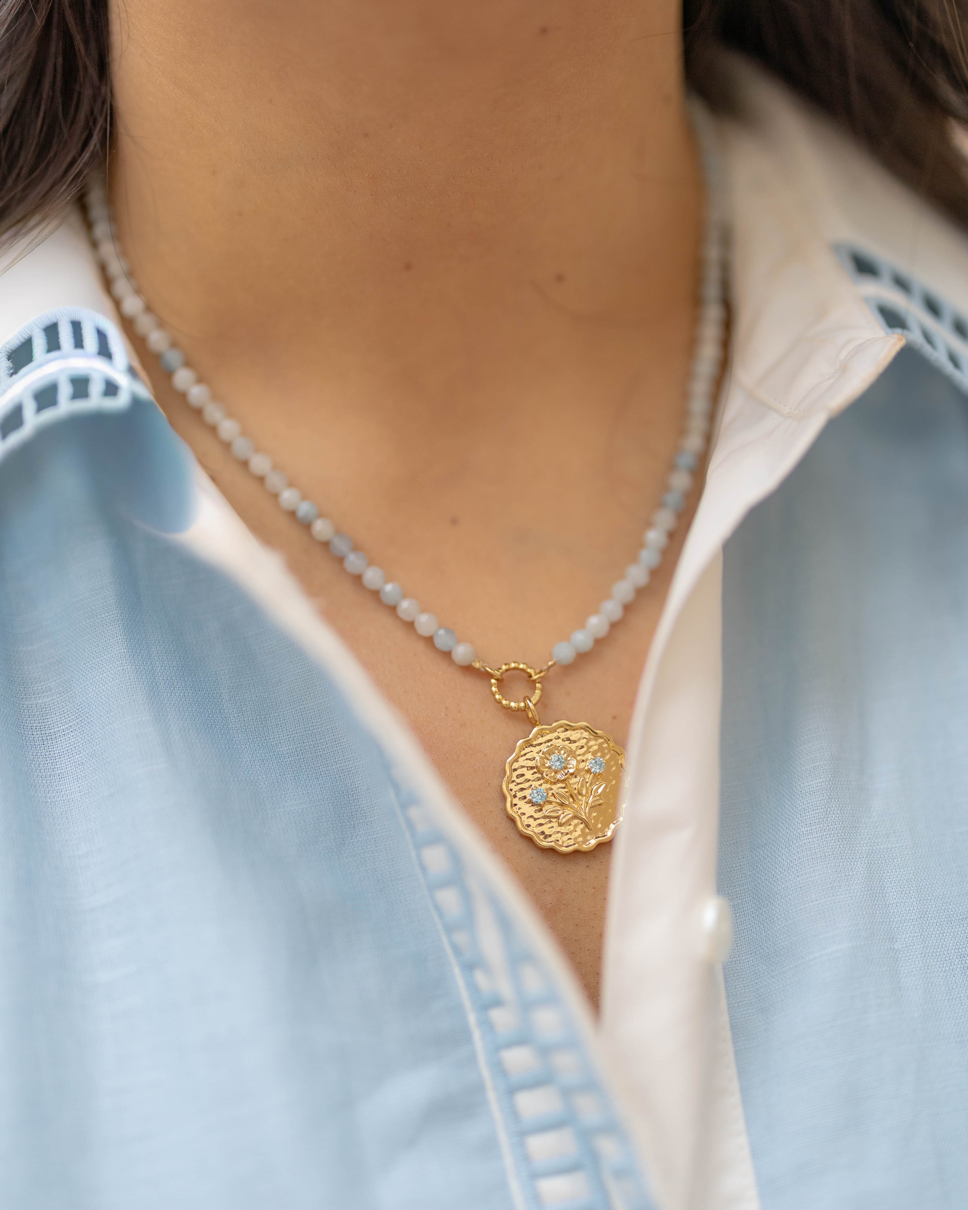 blue beaded necklace with a gold pendant floral charm with blue gemstones