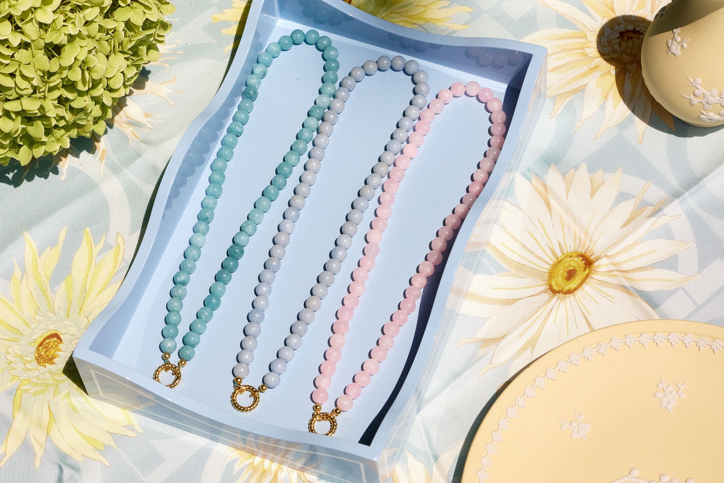 three beaded necklaces styled on a floral scarf with fresh flowers