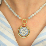 Necklace with a cameo floral pendant on a person wearing a striped shirt