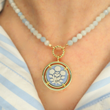 Necklace with a cameo floral pendant on a person wearing a striped shirt