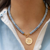 Close-up of a person wearing a blue beaded necklace with a gold pendant.