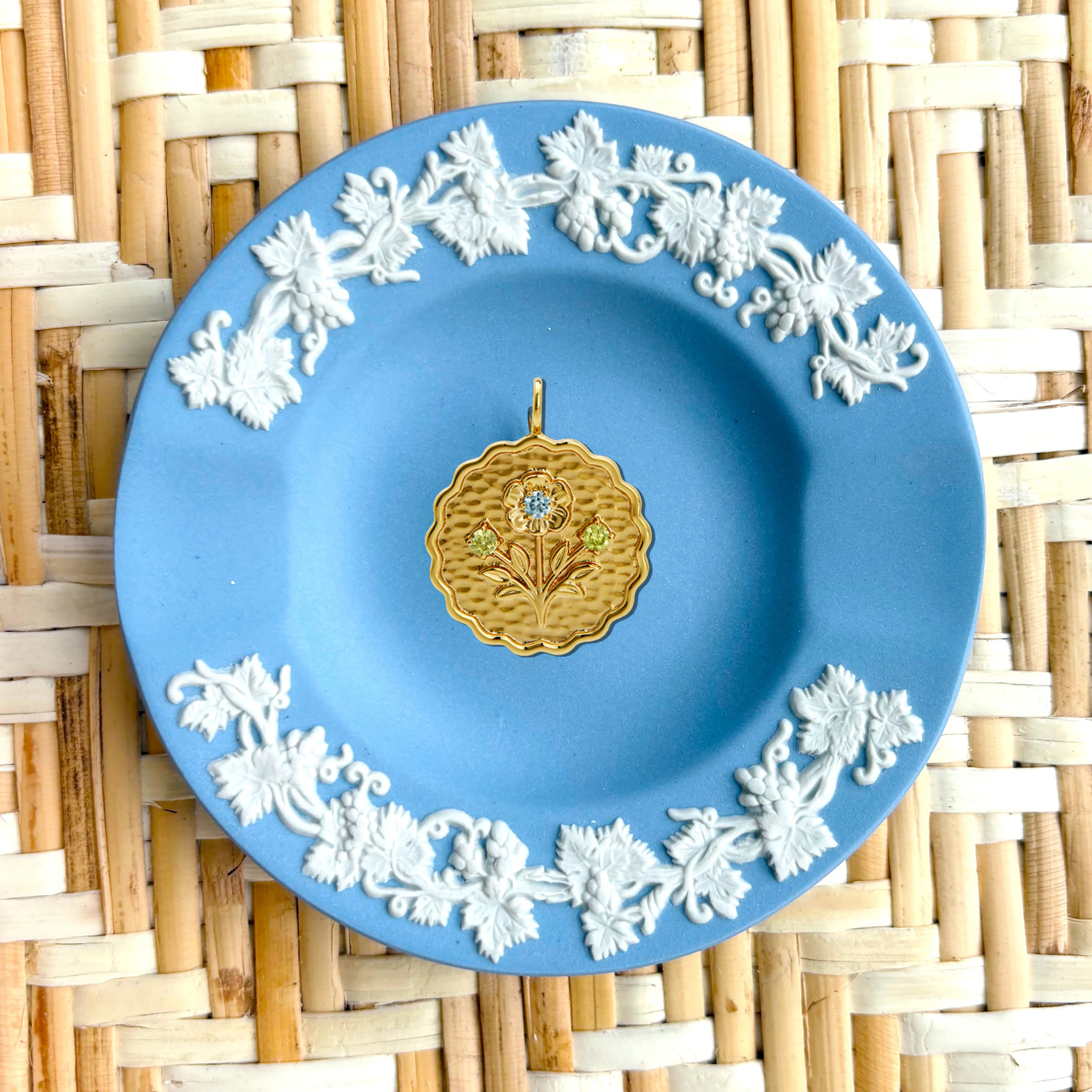 Decorative blue plate with white floral patterns and a gold center on a woven mat background