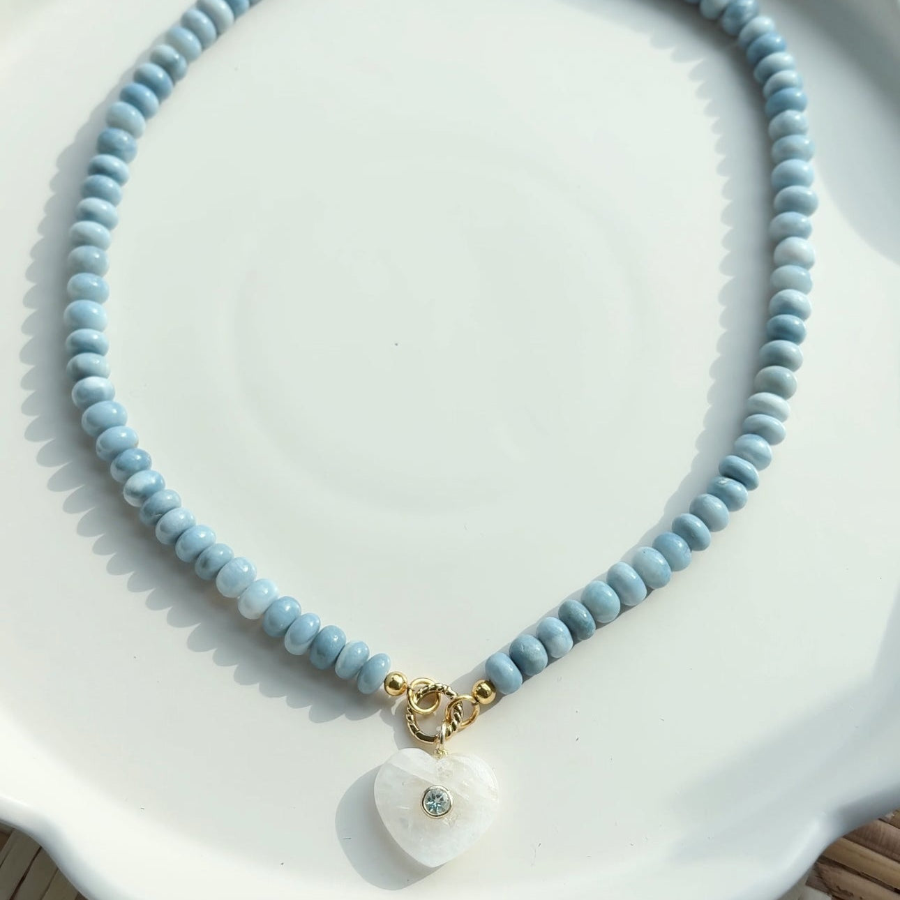 necklace with blue beads and heart shaped pendant on white tray