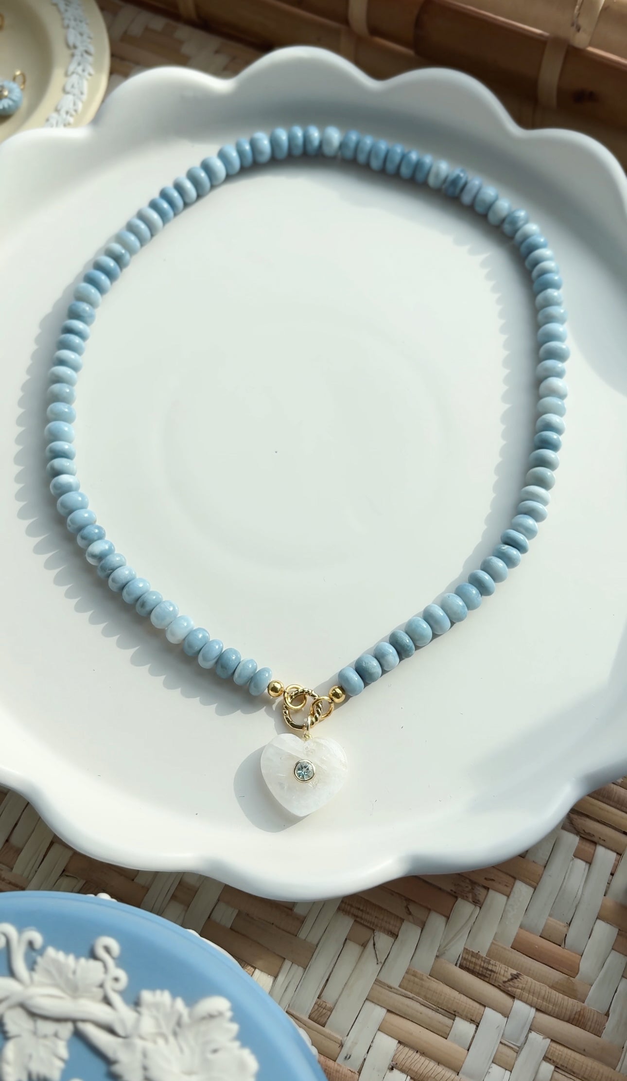 necklace with blue beads and heart shaped pendant on white tray