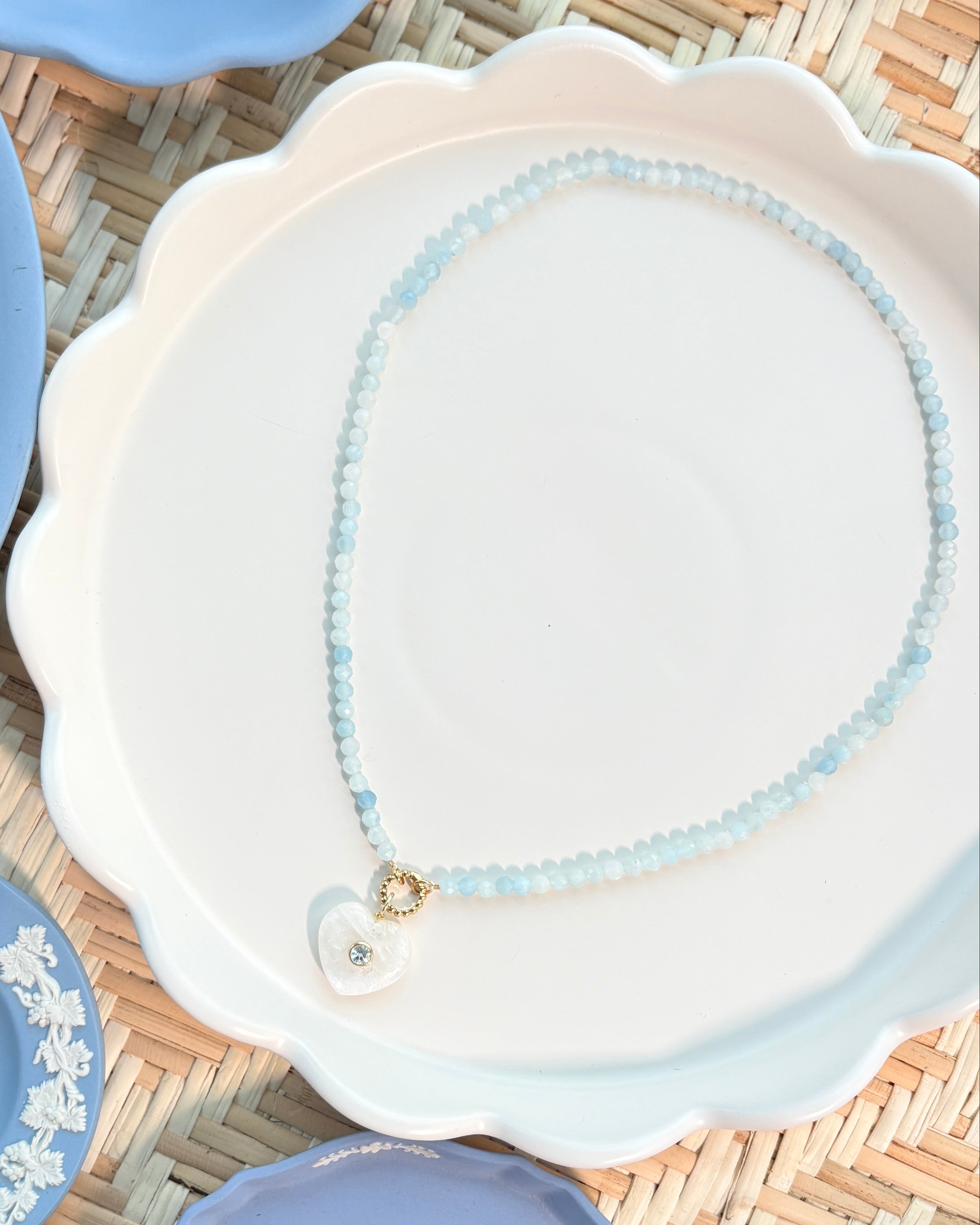 a moonstone shaped heart on a blue beaded necklace on a white plate