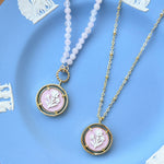 Two necklaces with pink pendants on a Wedgwood blue plate.