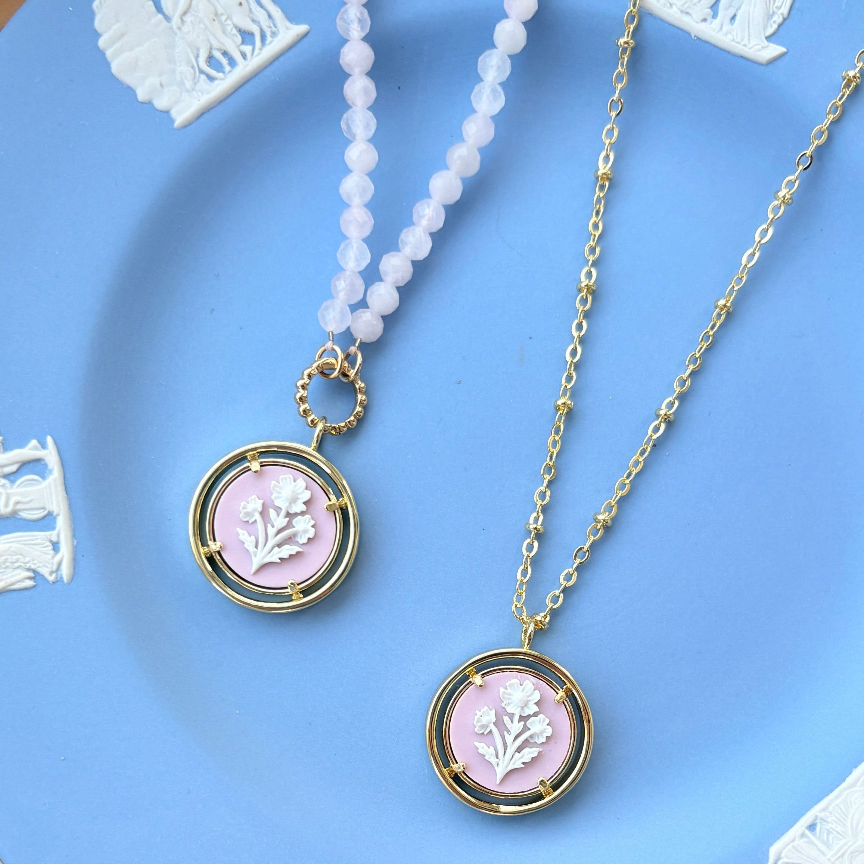 Two necklaces with pink pendants on a Wedgwood blue plate.