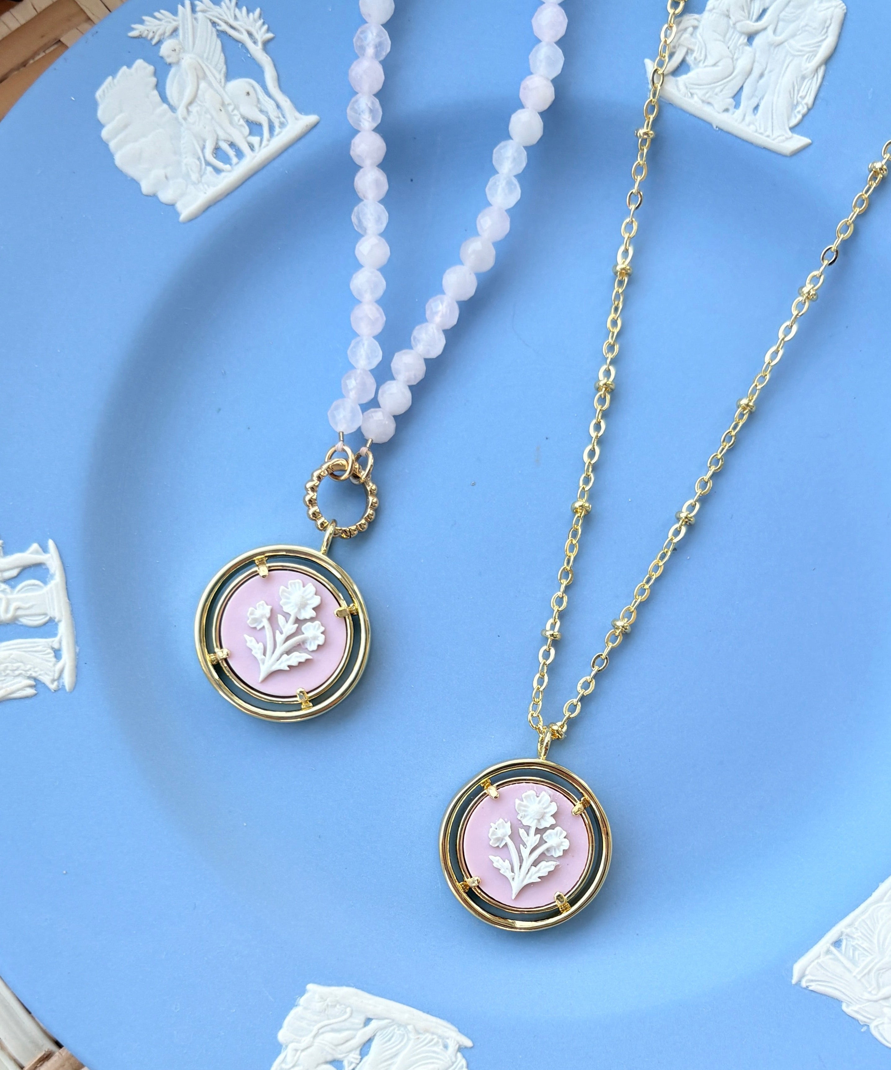 Two necklaces with pink pendants on a Wedgwood blue plate.