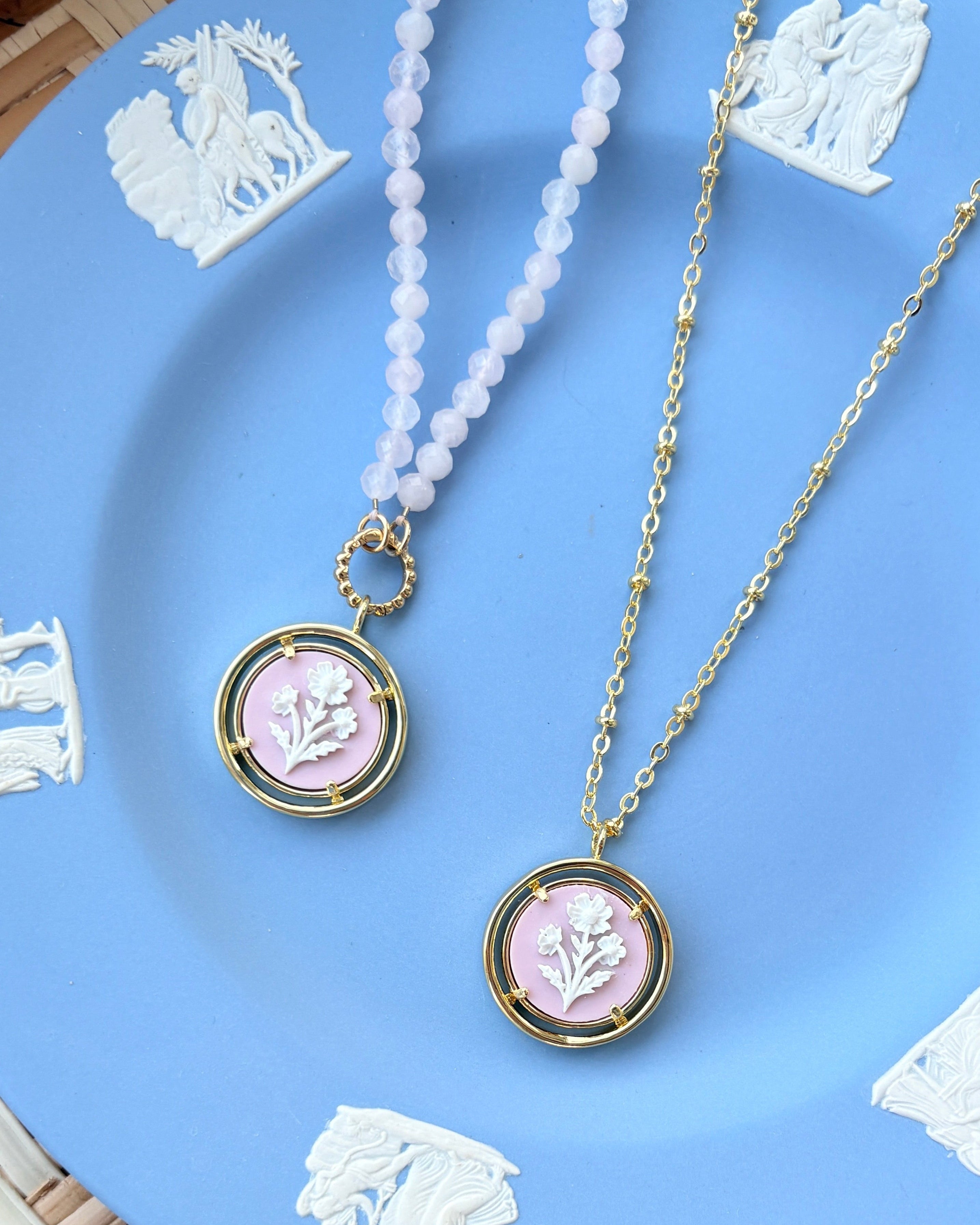 Two necklaces with pink pendants on a Wedgwood blue plate.