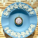 pink and gold cameo pendant on a blue plate