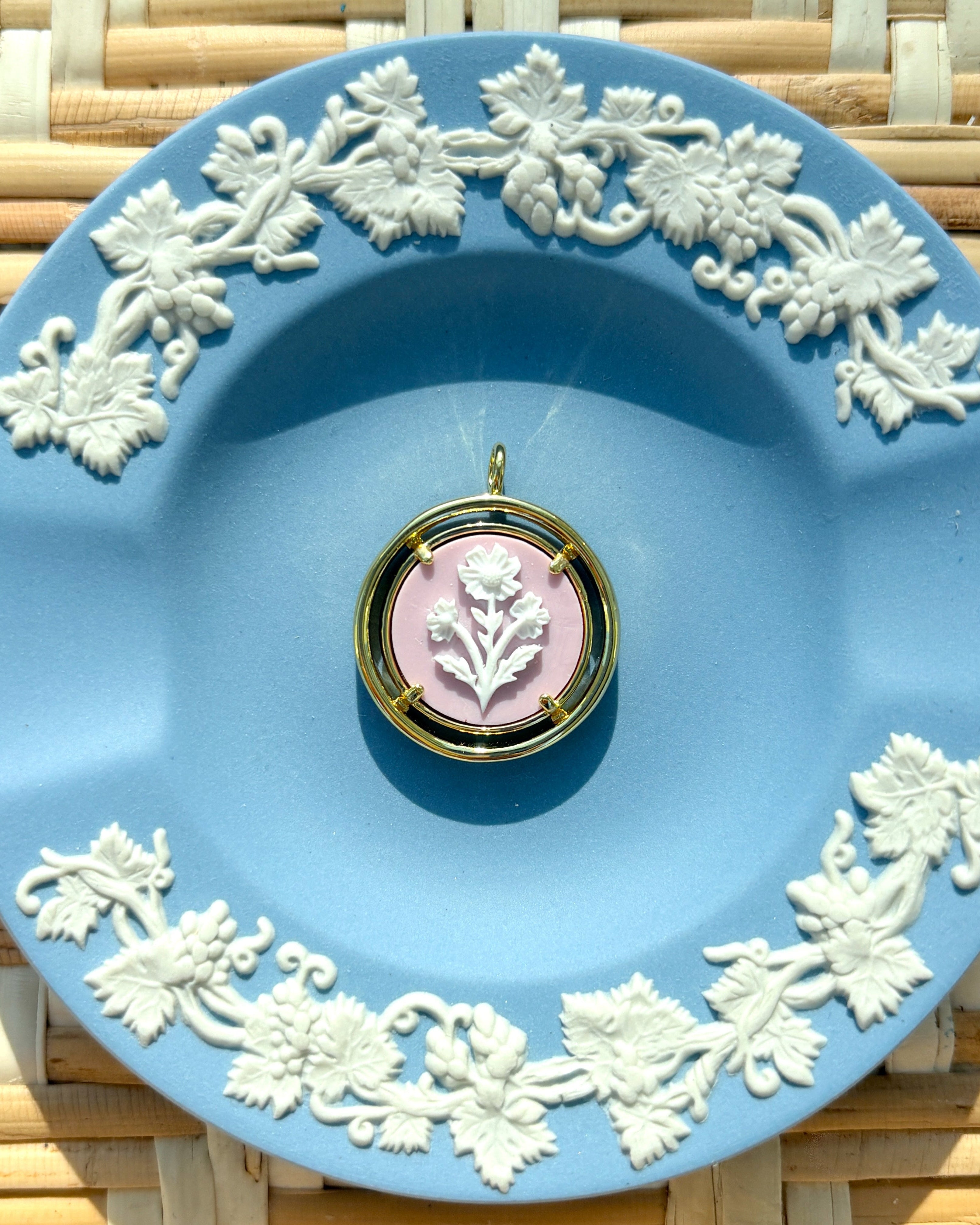pink and gold cameo pendant on a blue plate