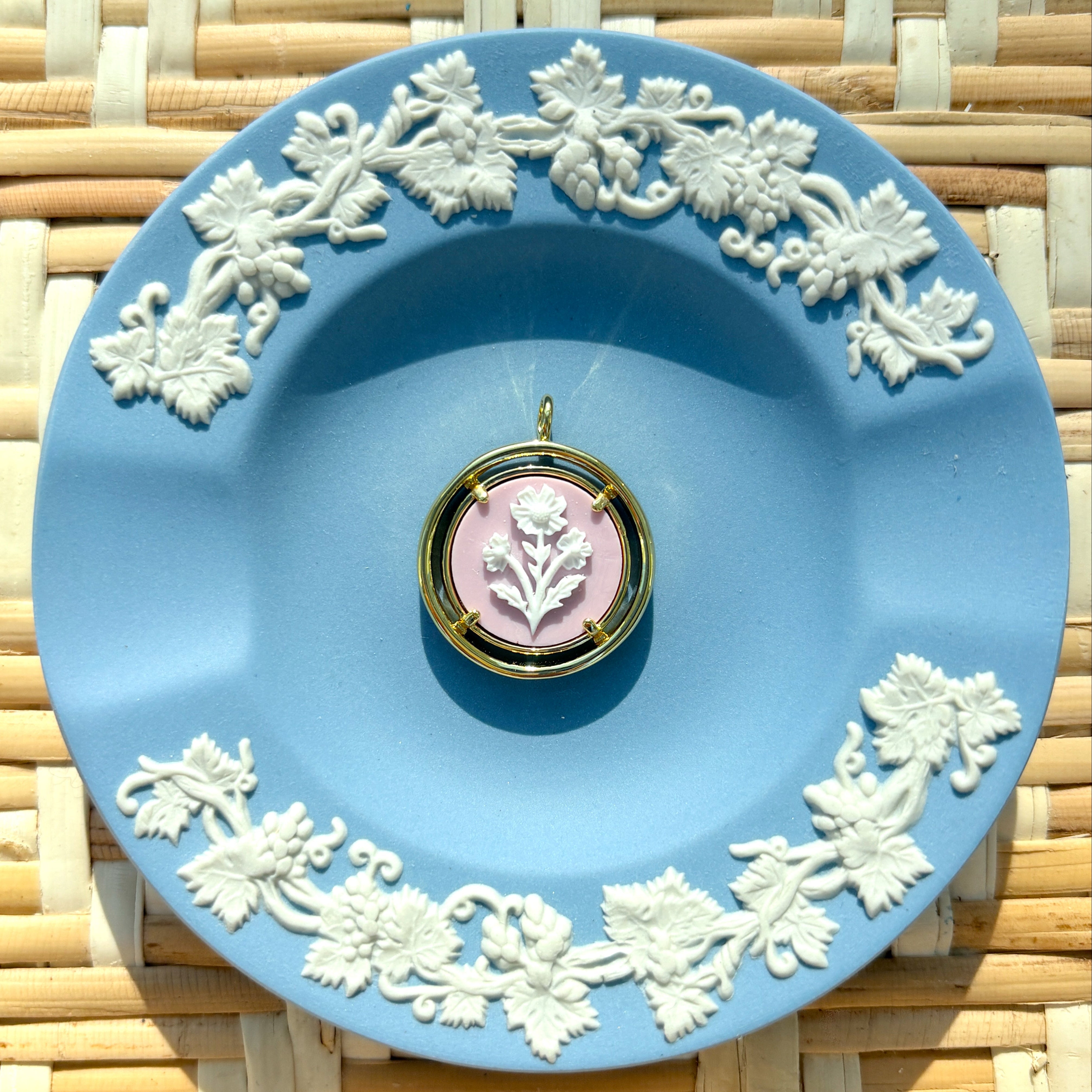 pink and gold cameo pendant on a blue plate