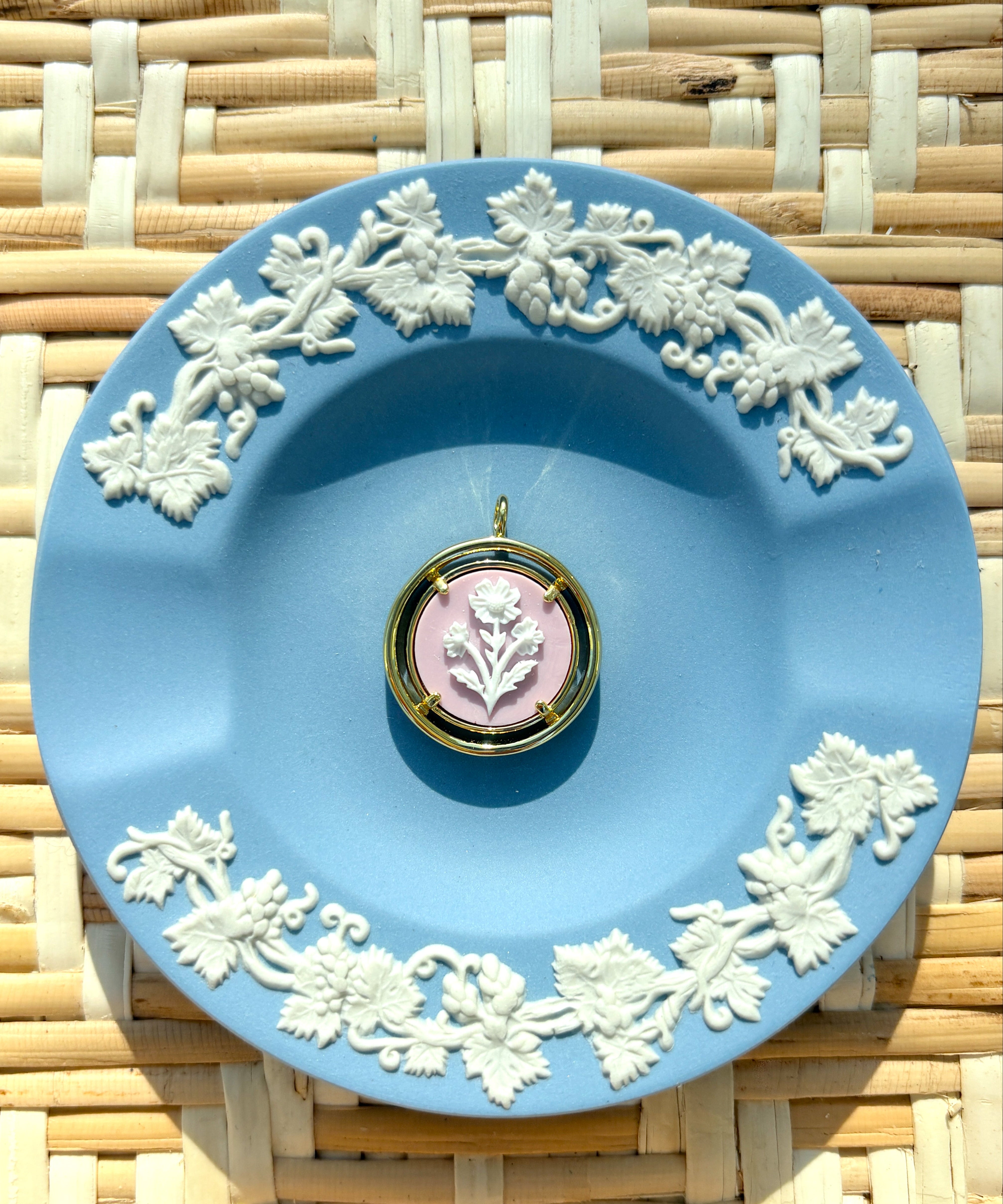 pink and gold cameo pendant on a blue plate