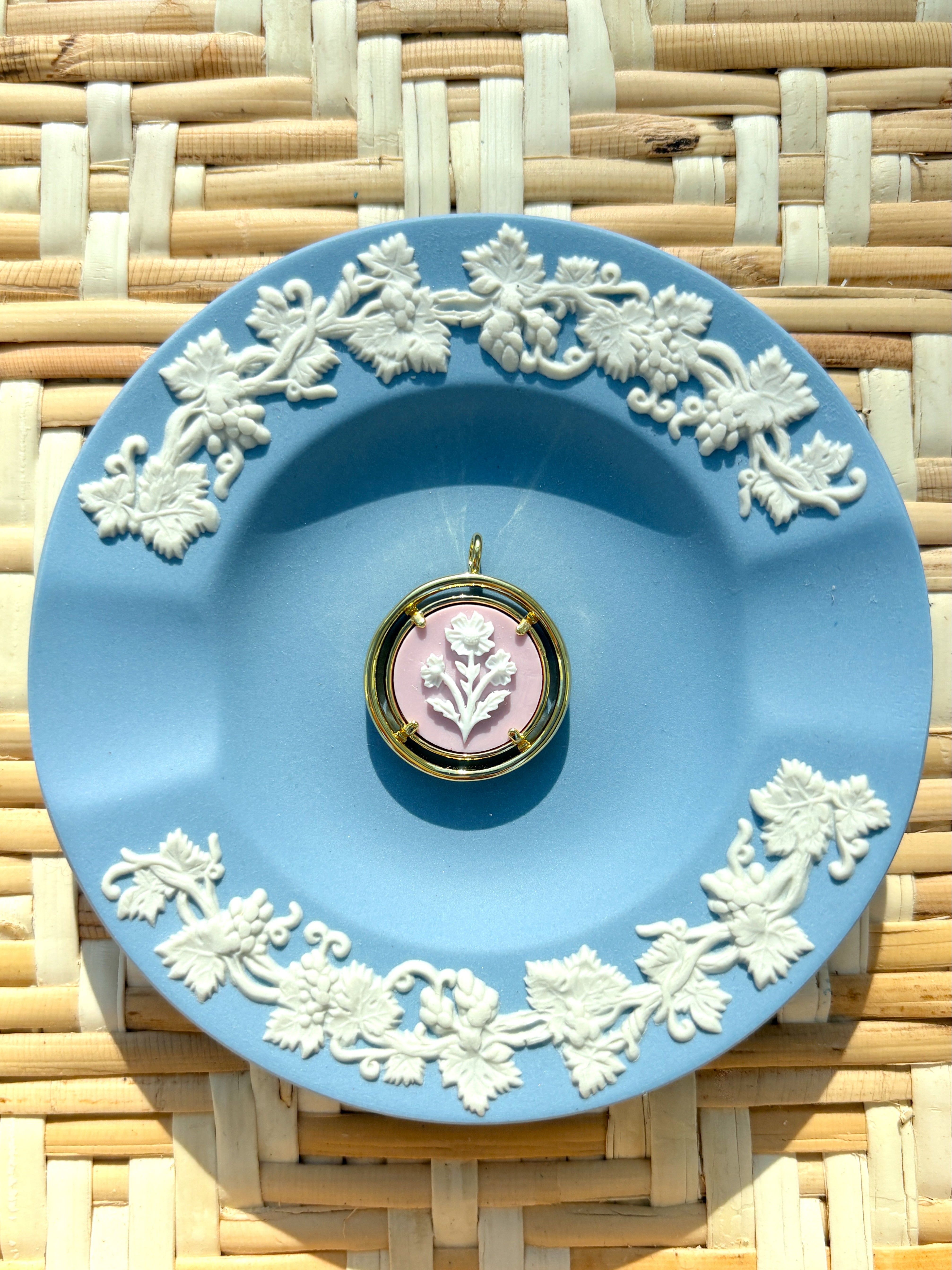 pink and gold cameo pendant on a blue plate