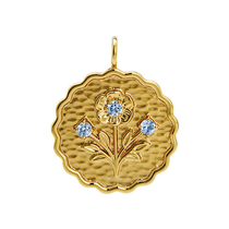 Gold pendant with floral design and blue gemstones on a white background