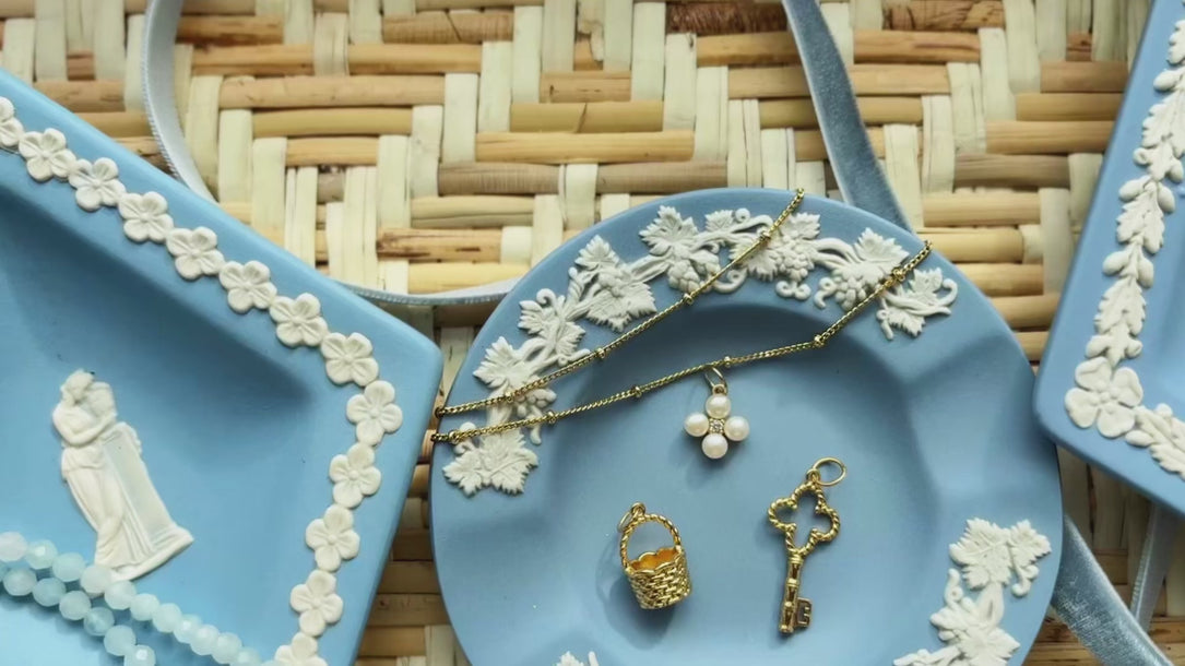 video of blue plates displaying golden charms and pearl jewelry