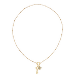 Golden necklace with a key-shaped charm and clover charm on a white background