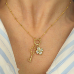 Golden necklace with a key and clover pendant on a person wearing a striped shirt