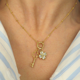 Golden necklace with a key and clover pendant on a person wearing a striped shirt